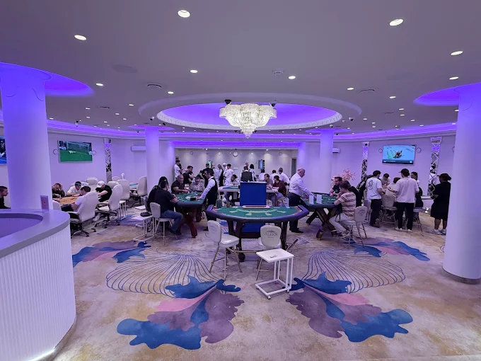 The live table floor, busy with players and dealers under the chandelier